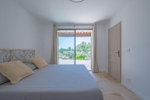 埃吉莱VILLA VOGA- Luxury family holidays Aix-en-Provence的白色卧室设有一张大床和一个滑动玻璃门