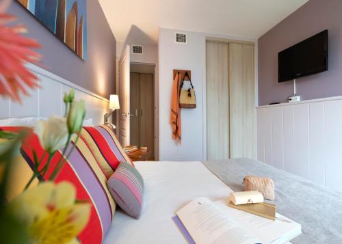 比亚里茨Résidence Pierre & Vacances Premium Haguna的酒店客房设有一张带书籍的床和一台电视。