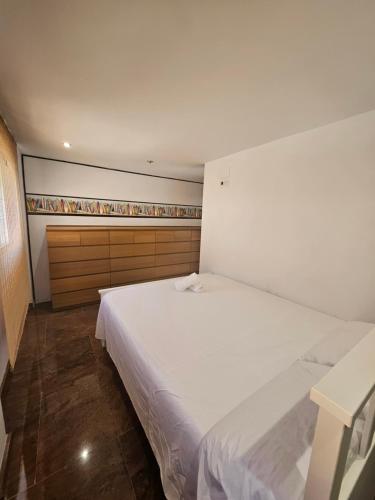 库列拉Chalet adosado的卧室配有一张白色大床和木制橱柜。
