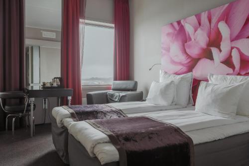 卑尔根卑尔根机场凯瑞酒店的一间卧室配有一张大床和粉红色的花床头板