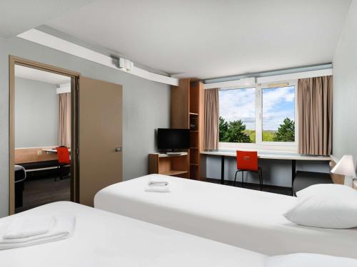 布达佩斯Ibis Budapest Citysouth的酒店客房配有两张床和一张书桌