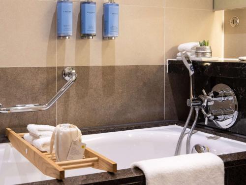 希灵登索菲特伦敦希斯罗酒店的带浴缸的浴室和毛巾托盘