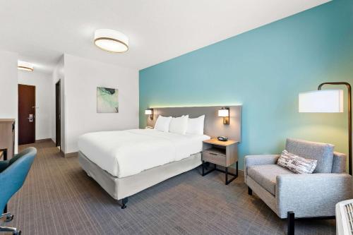 TunkhannockComfort Inn & Suites的配有一张床和一把椅子的酒店客房