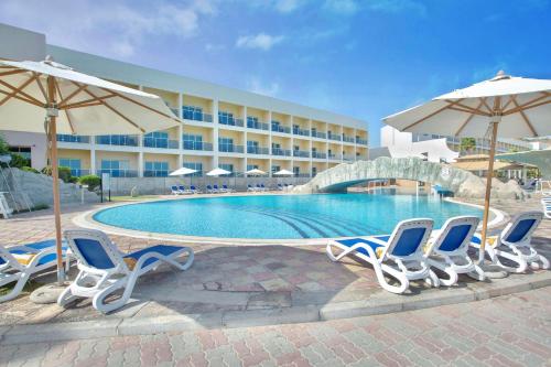 迪巴富吉拉丽笙度假酒店的酒店旁的游泳池配有椅子和遮阳伞