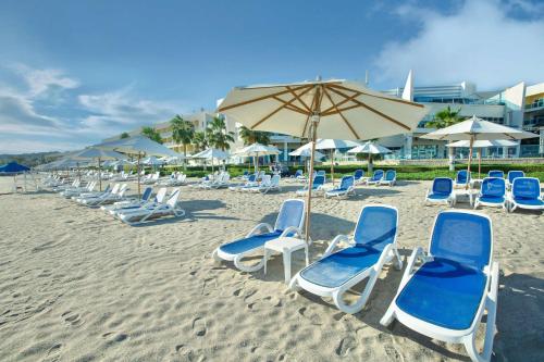 迪巴富吉拉丽笙度假酒店的海滩上的一组椅子和一把遮阳伞