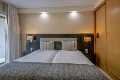 阿尔布费拉Areias Village Beach Suite Hotel的一间卧室配有一张大床和两个枕头