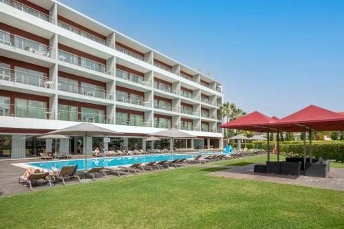 阿尔布费拉Areias Village Beach Suite Hotel的一个带游泳池、椅子和遮阳伞的酒店