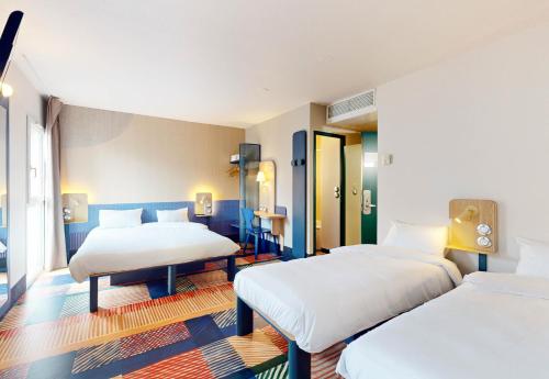 南特B&B HOTEL Nantes Centre的一间带两张床的卧室和一间带两张桌子的房间