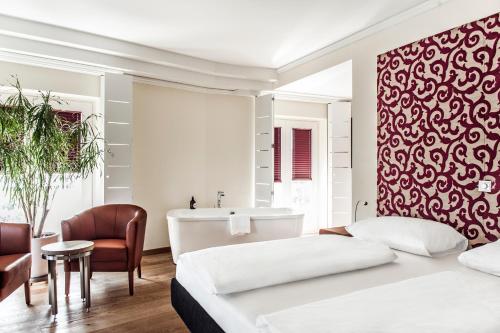 格拉茨Hotel Weitzer Graz - Centre of Graz的一间卧室配有一张床,浴室设有浴缸