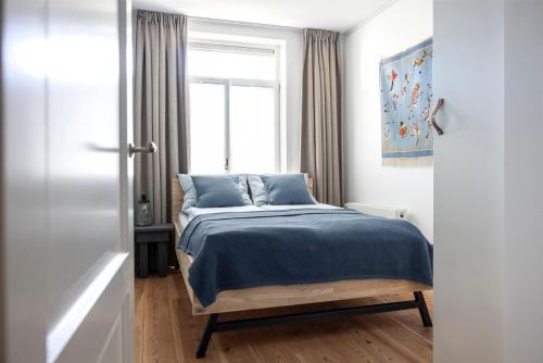 阿姆斯特丹Gorgeous And Stylish Place For Two In Hip West!的一间卧室配有一张带蓝色床单的床和一扇窗户。