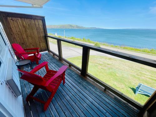 迪格比Admiral Digby Inn Restaurant and Cottages的海景甲板上的两张红色椅子
