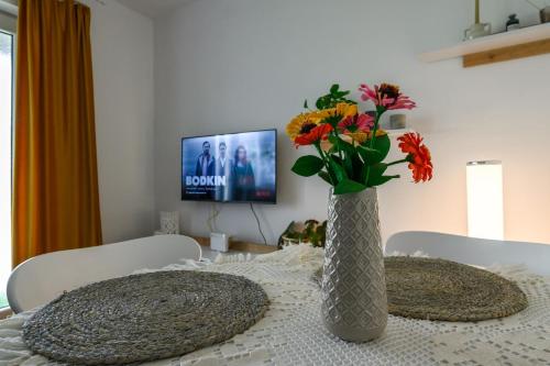 比斯特里察Apartament Corina cu parcare的花瓶,桌子上放着鲜花,还有电视机