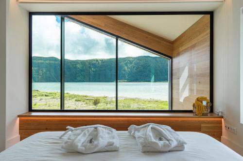 蓬塔德尔加达Sete Cidades Lake Cabin - Casa da Lagoa的一间卧室设有大窗户,床上配有毛巾