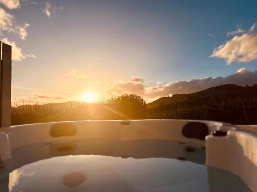 皮特洛赫里Kinnaird Woodland Lodges的背景为带日落的浴缸