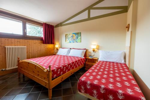 SerradaRESIDENCE SERRADA的小客房内的两张床,配有红色床单