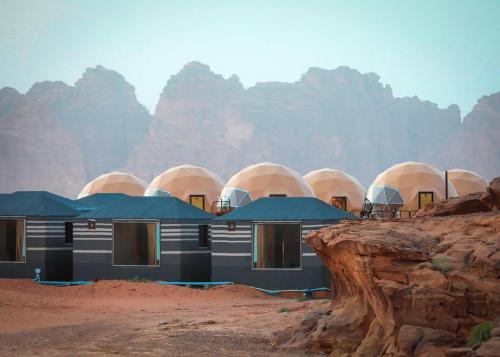 瓦迪拉姆Faisal Wadi Rum camp的沙漠中的一座建筑,以群山为背景
