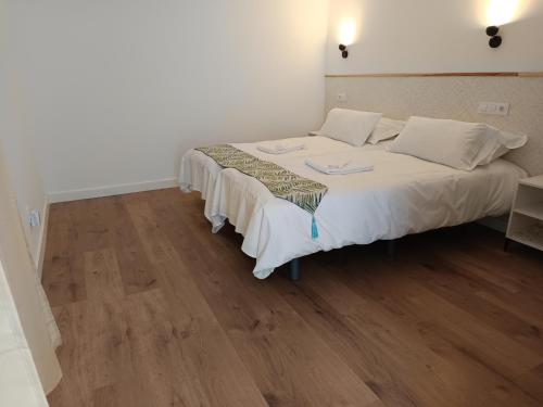 孔苏埃格拉SG ROOMS的一间卧室配有一张铺有木地板的白色床单。