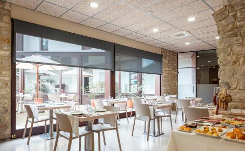 贝萨卢卡萨马歇尔酒店的餐厅设有白色的桌椅和窗户。