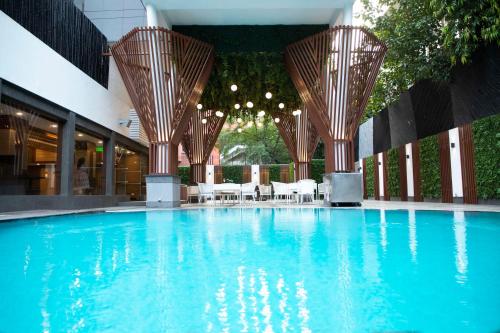 新德里Park Inn by Radisson,South Delhi的大楼内带桌椅的大型游泳池