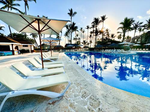 蓬塔卡纳Sunscape Coco Punta Cana - All Inclusive的一组躺椅和一把遮阳伞,位于游泳池旁