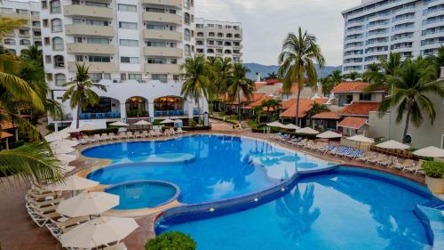 伊斯塔帕Tesoro Ixtapa Beach Resort的享有带椅子和遮阳伞的游泳池的上方景色