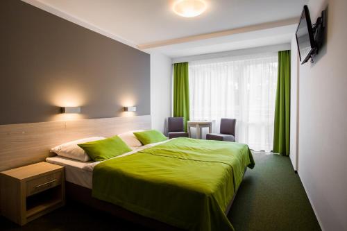 库瑞尼卡慕斯卡Hotel *** NAT Krynica Morska的酒店客房设有一张绿色的床和一个窗户。