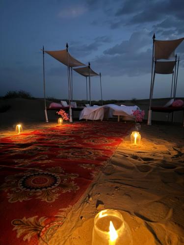 斋沙默尔Best Desert Camp In Jaisalmer Red Velvet的沙漠中带蜡烛和遮阳伞的房间