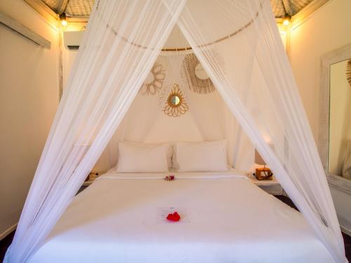 吉利美诺Ora Villas Gili Meno的一间卧室配有一张白色的床,上面有两朵玫瑰花