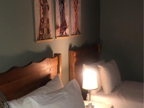 穆西纳Munati B&B的一间卧室配有两张床、一盏灯和绘画作品