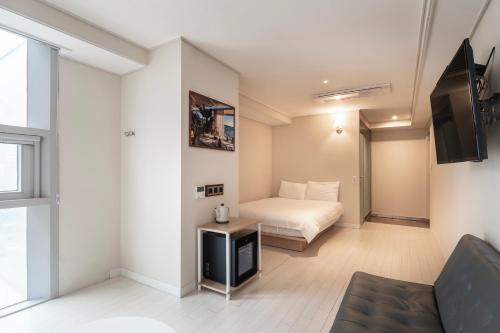 釜山艾丽西亚精品酒店的一间卧室配有一张床,并在一间客房内配有电视。