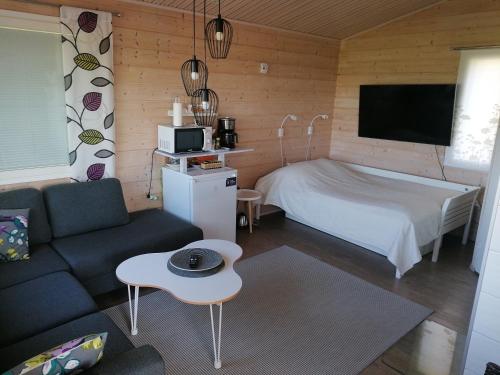 NivalaViihtyisä saunamökki päärakennuksen takana, oma rauha的一间卧室配有一张床、一张沙发和一台电视。