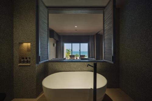 宫古岛アヤンナ宮古島的一间带白色浴缸和窗户的浴室