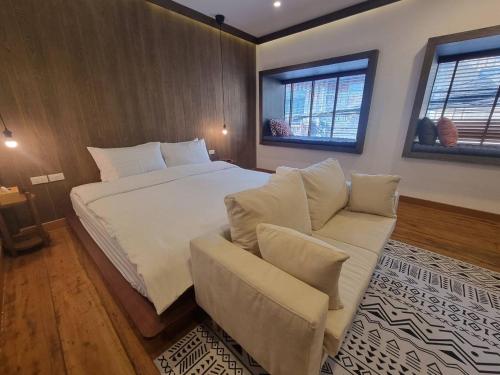 清刊The Folkster House Chiangkhan的一间卧室配有一张床、一张沙发和两个窗户。