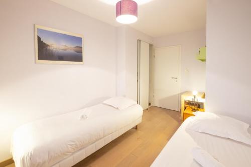 安锡Printemps chaleureux T4 +2 place de parking privée的白色的客房设有两张床,墙上挂着一张照片