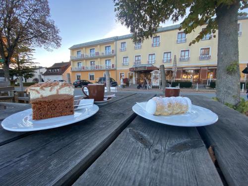 巴特塔茨曼斯多夫Simon - Hotel & Café的木桌旁的两片蛋糕