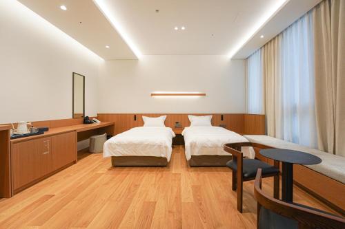 釜山Hotel Ground27的酒店客房设有两张床和一张桌子。