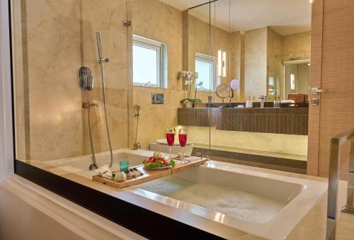迪马普尔Shulem Boutique Hotel的带淋浴和两杯葡萄酒的浴缸的浴室