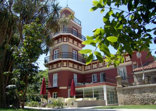 列尔加内斯Gastro Hotel La Giraldilla的一座红色的大建筑,配有椅子和遮阳伞