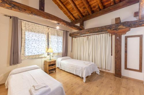 Santa María la Real de NievaLa Casona y Casitas de Tabladillo的配有木天花板的客房设有两张床。