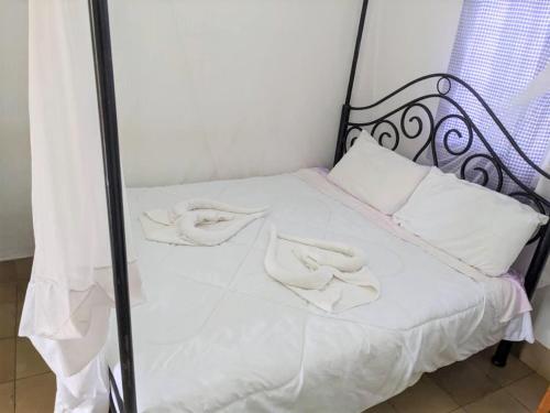 OldeaniSTC.SAFARI LODGE的一张带白色床单和白色枕头的床