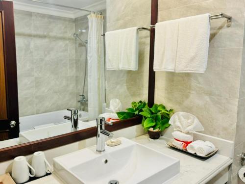 荣市穆尔泰东方大酒店的浴室配有盥洗盆、镜子和浴缸