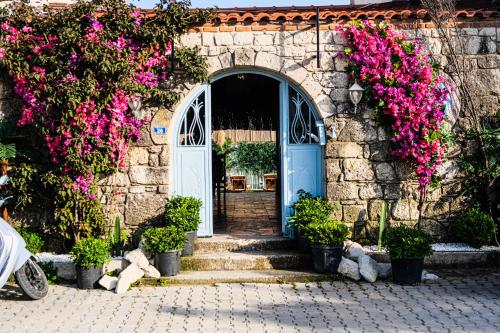 阿拉恰特多特麦维斯姆阿拉卡提酒店的一座石头建筑,有蓝色的门和粉红色的花朵