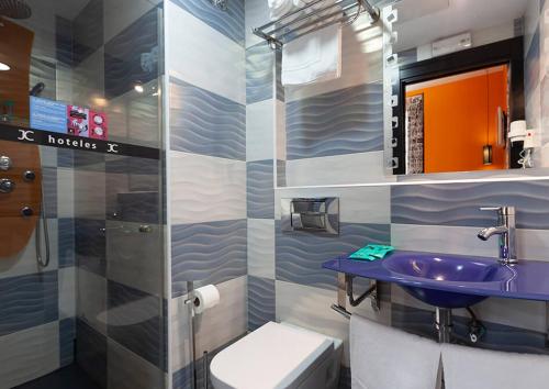 马德里JC客房圣多明各酒店的一间带紫色水槽和卫生间的浴室
