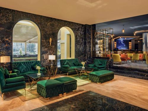 十月六日城Mövenpick Hotel Cairo - Media City的客厅配有绿绿绿沙发和椅子