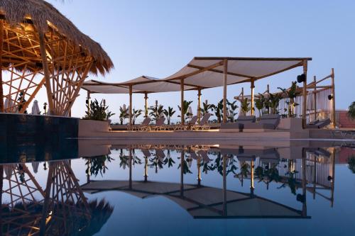 赫索尼索斯海星村酒店的水边带桌子和遮阳伞的游泳池