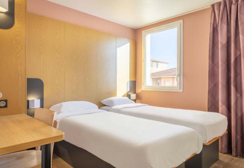 布克港B&B HOTEL Martigues Port-de-Bouc的窗户房间里一排床
