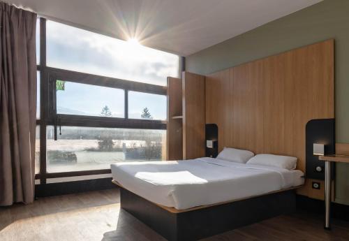 格勒诺布尔B&B HOTEL Grenoble Centre Verlaine的一间卧室设有一张大床和一个大窗户