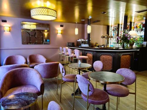 贝尔韦Logis Hôtel Le Boudoir的一间酒吧,里面配有紫色椅子和桌子