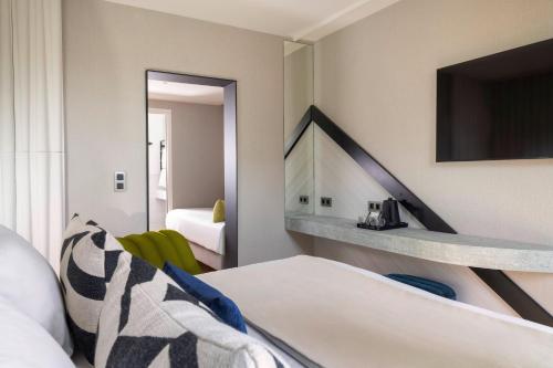 巴黎Hôtel Raspail Montparnasse的一间酒店客房,配有一张床和一台电视