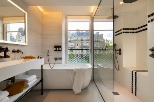 巴黎Hôtel Raspail Montparnasse的白色的浴室设有浴缸和窗户。